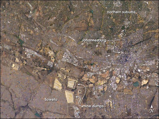 Vista orbital de Joanesburgo com manchas claras de depósitos de rejeitos entre áreas urbanizadas, ilustrando artigo Mineração em Joanesburgo: como o ouro dividiu a cidade?