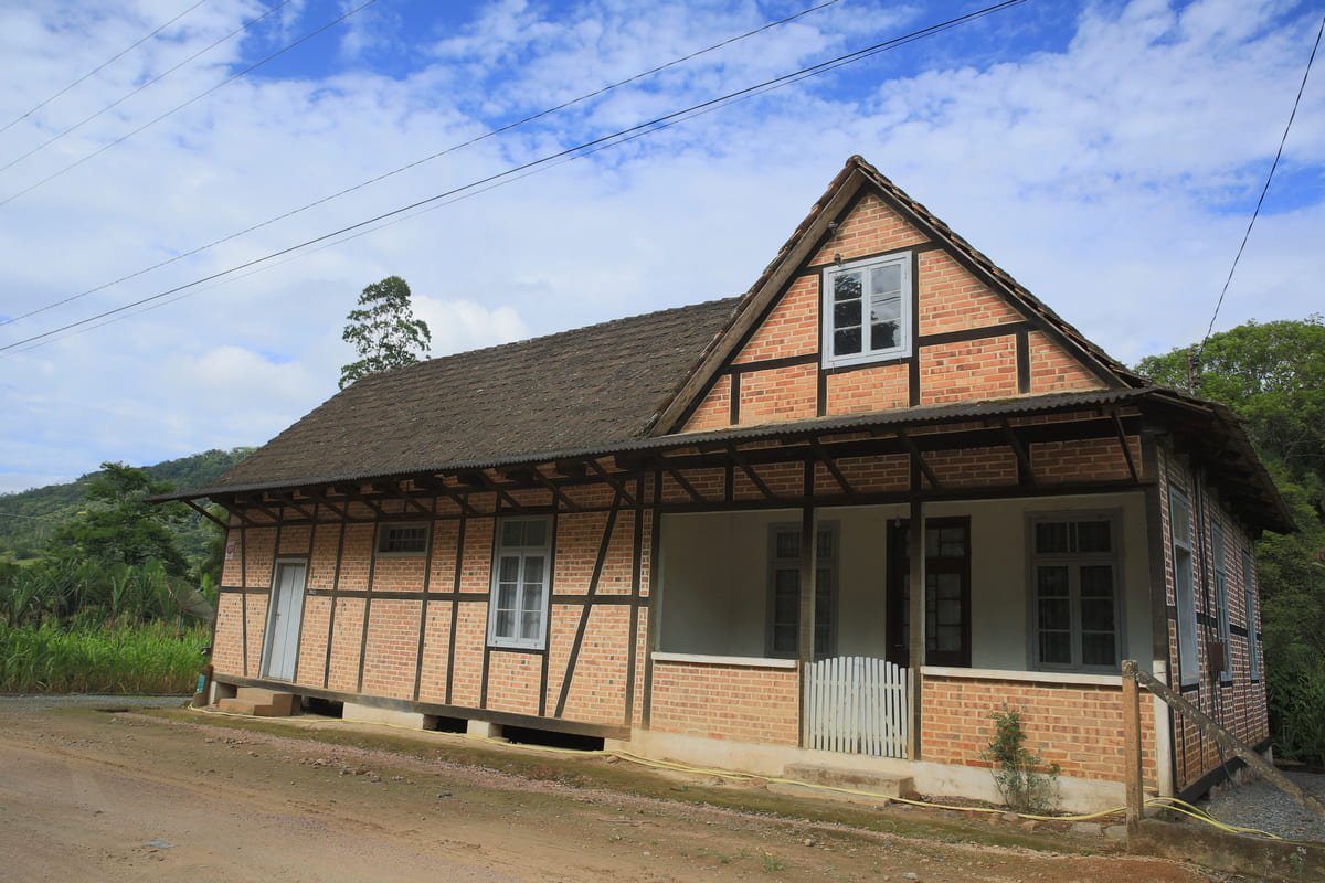 Casa enxaimel em Testo Alto, com terreno aberto e encosta arborizada ao fundo, ilustrando artigo Paisagem rural de Pomerode: o que se preserva além das casas?