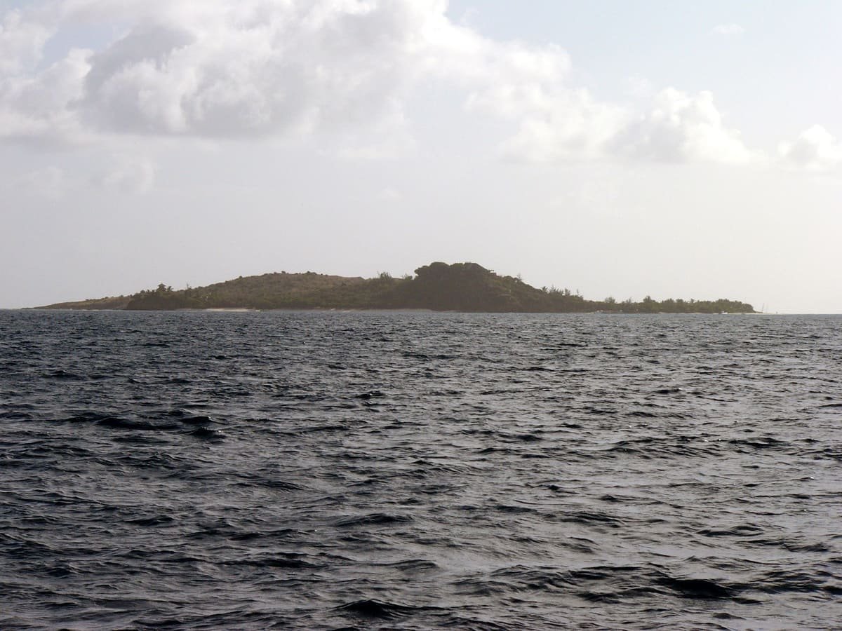 Necker Island vista do mar, com praia, vegetação e construções no alto. Ilustrando artigo Ilhas privadas: quem controla o acesso ao território?
