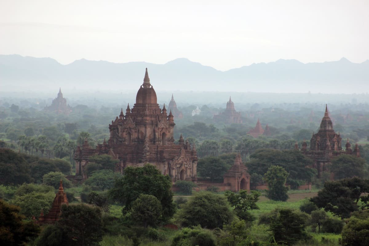 Monumentos de diferentes alturas entre árvores na planície de Bagan, ilustrando artigo Templos de Bagan: por que tantos foram construídos ali?