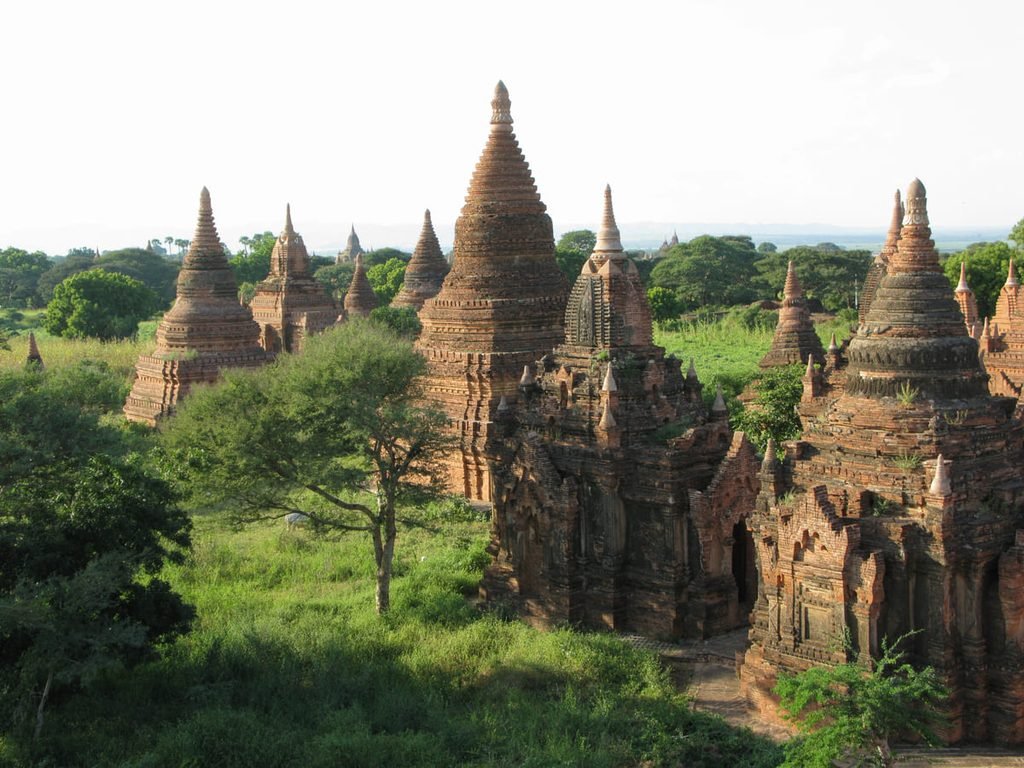 Construções religiosas de tijolos entre árvores e caminhos em Bagan, ilustrando artigo Templos de Bagan: por que tantos foram construídos ali?