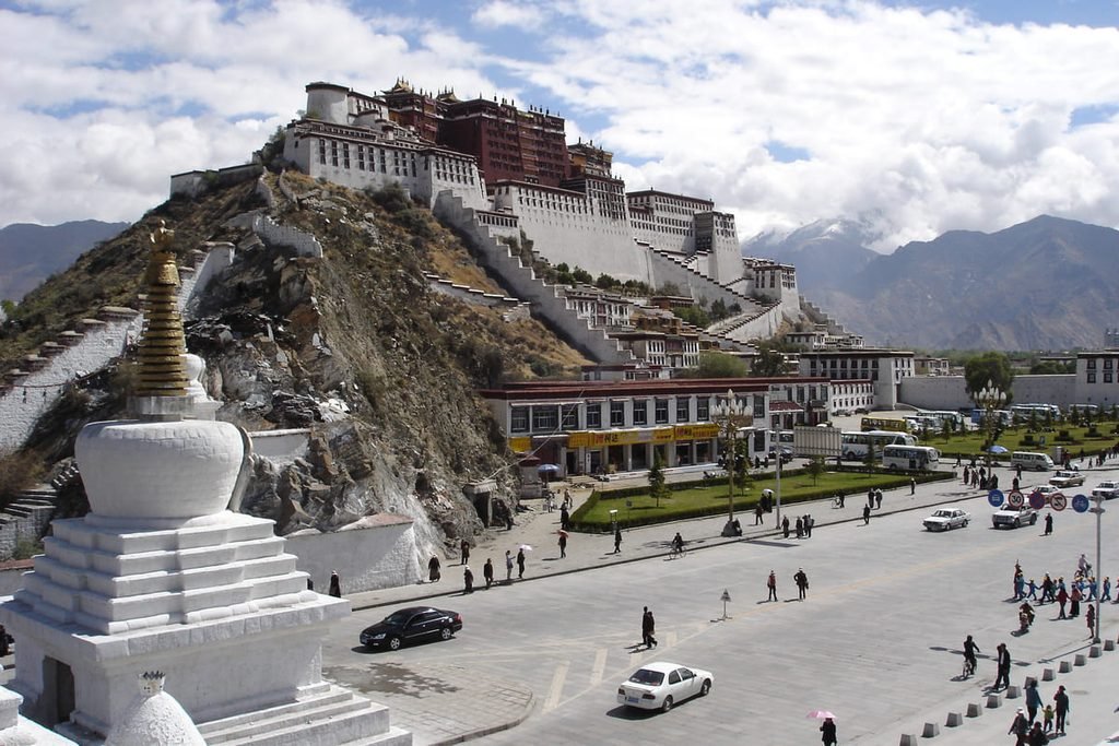 Palácio do Potala sobre uma elevação em Lhasa, com construções urbanas à sua frente. Ilustrando artigo Lugares sagrados do Himalaia: como organizam a paisagem?