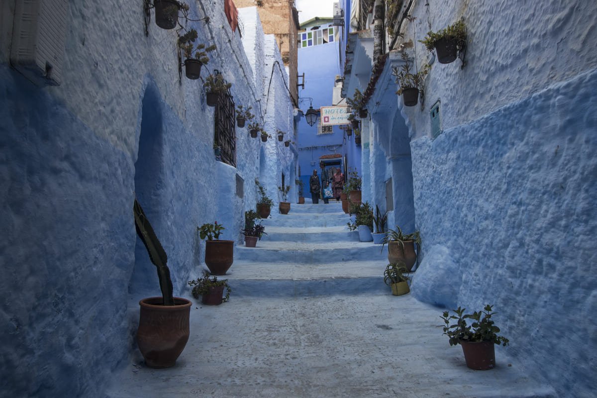Rua de Chefchaouen com paredes e degraus em diferentes tons de azul e superfícies brancas. Ilustrando artigo Cidades azuis: por que a cor aparece de formas diferentes?
