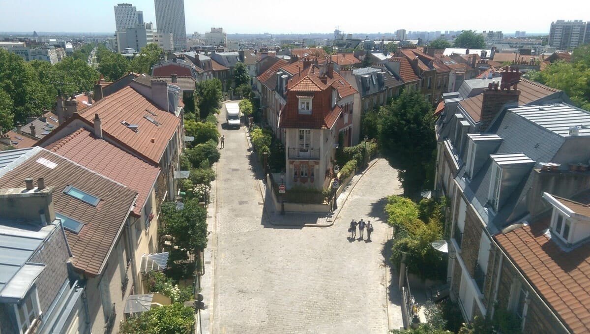 Casas, jardins e duas ruas de La Campagne à Paris, com edifícios mais altos ao fundo. Ilustrando artigo Paisagens de Paris: por que são tão diferentes?