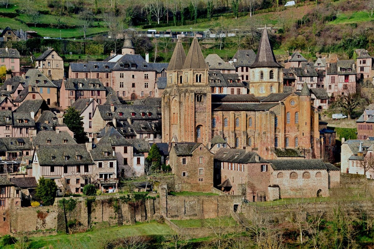 Igreja da abadia de Sainte-Foy cercada por casas de pedra e madeira na encosta de Conques. Ilustrando artigo Vilarejos franceses: o que há de medieval na paisagem?