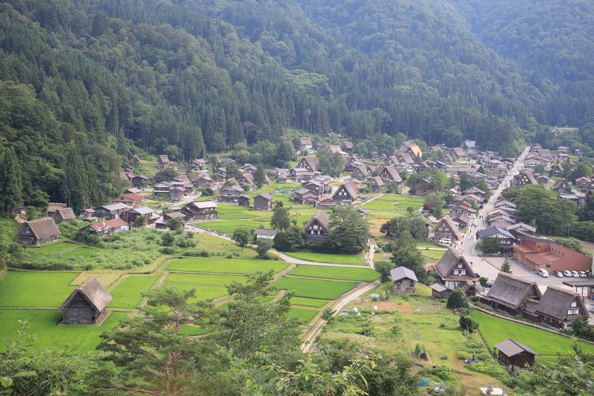 Vista de Ogimachi com casas de telhados inclinados, campos verdes e encostas florestadas. Ilustrativo ao artigo Japão rural: o que as casas revelam sobre o território?
