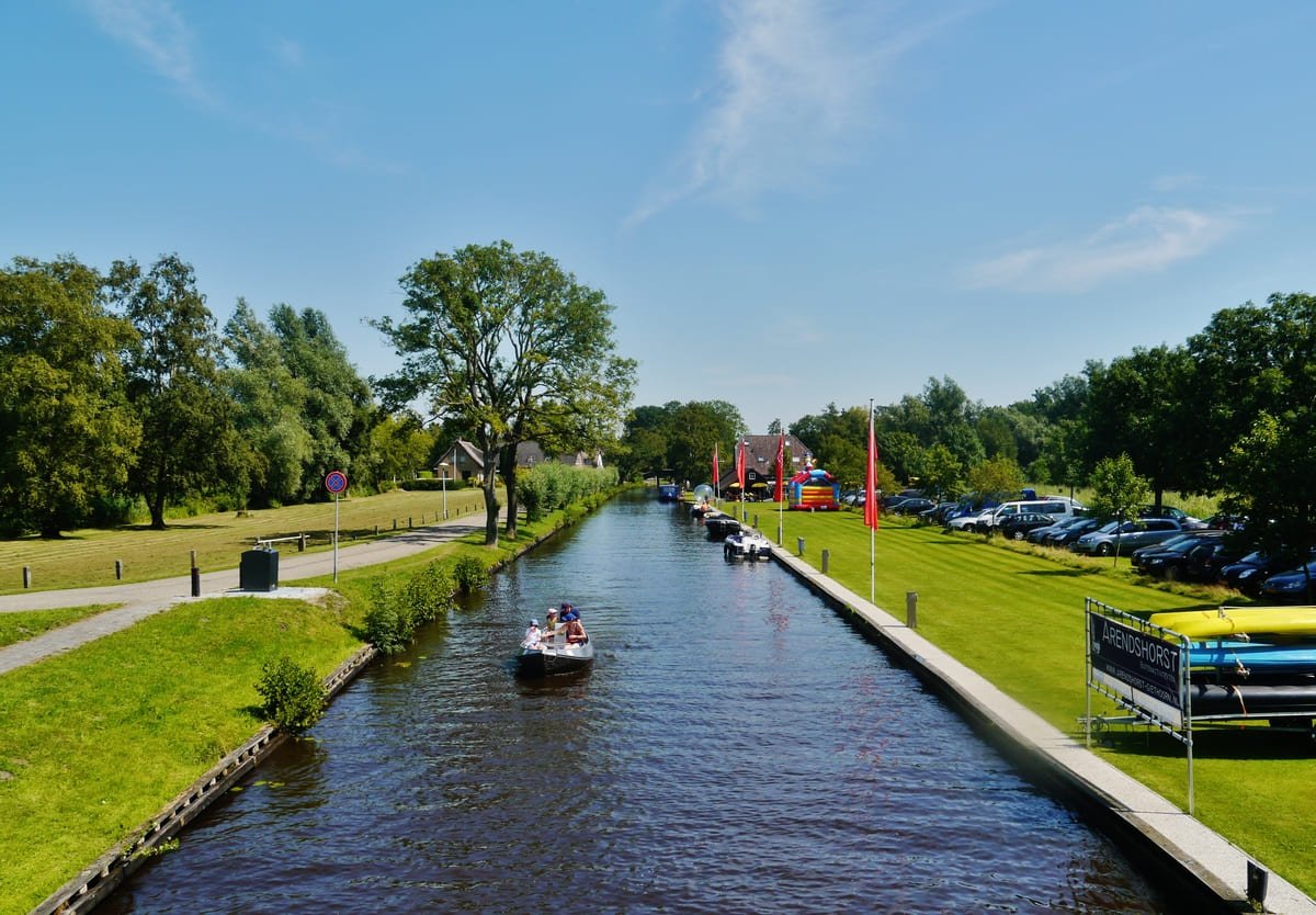 Canal de Giethoorn com barcos, caminhos nas margens, árvores e carros estacionados. Ilustrativo ao artigo Vilarejos nos Países Baixos: o que a água explica?