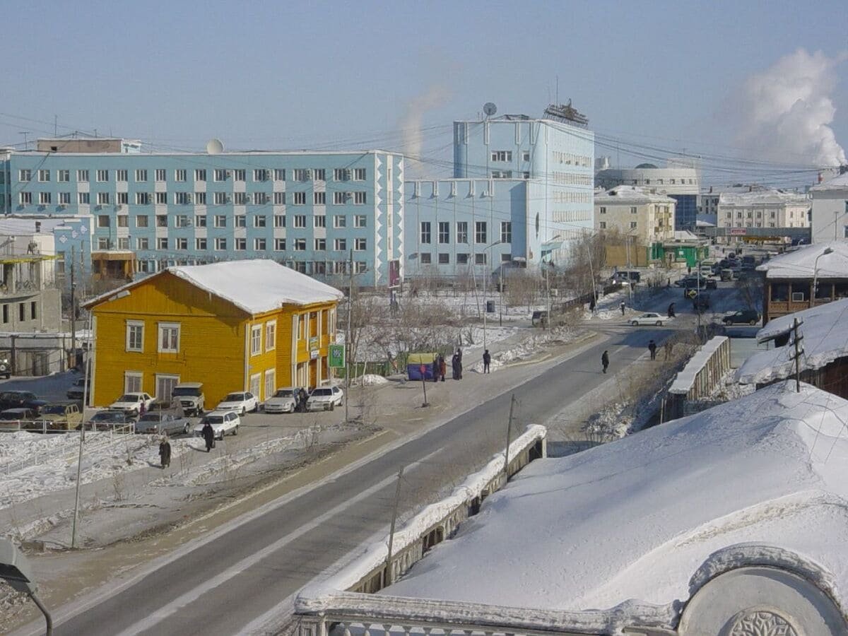 Rua de Yakutsk com veículos, pedestres, edifícios e neve nas calçadas e nos telhados. Ilustrando artigo Frio extremo na Rússia: por que a Sibéria esfria tanto?