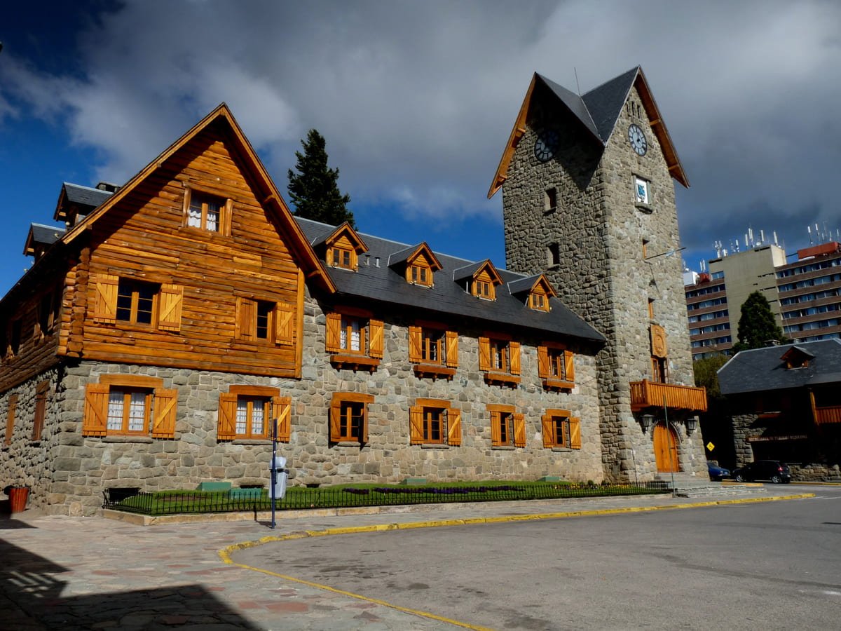 Fachadas de pedra e madeira e torre com relógio no Centro Cívico de Bariloche. Ilustrando artigo Bariloche revelada: como explorar cidade, circuito e porto?