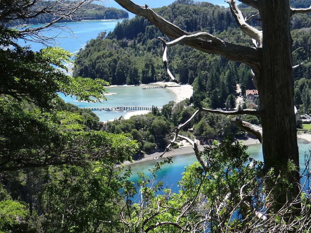 Istmo de Quetrihué visto de um mirante, com praias, cais e águas do Nahuel Huapi entre áreas arborizadas.