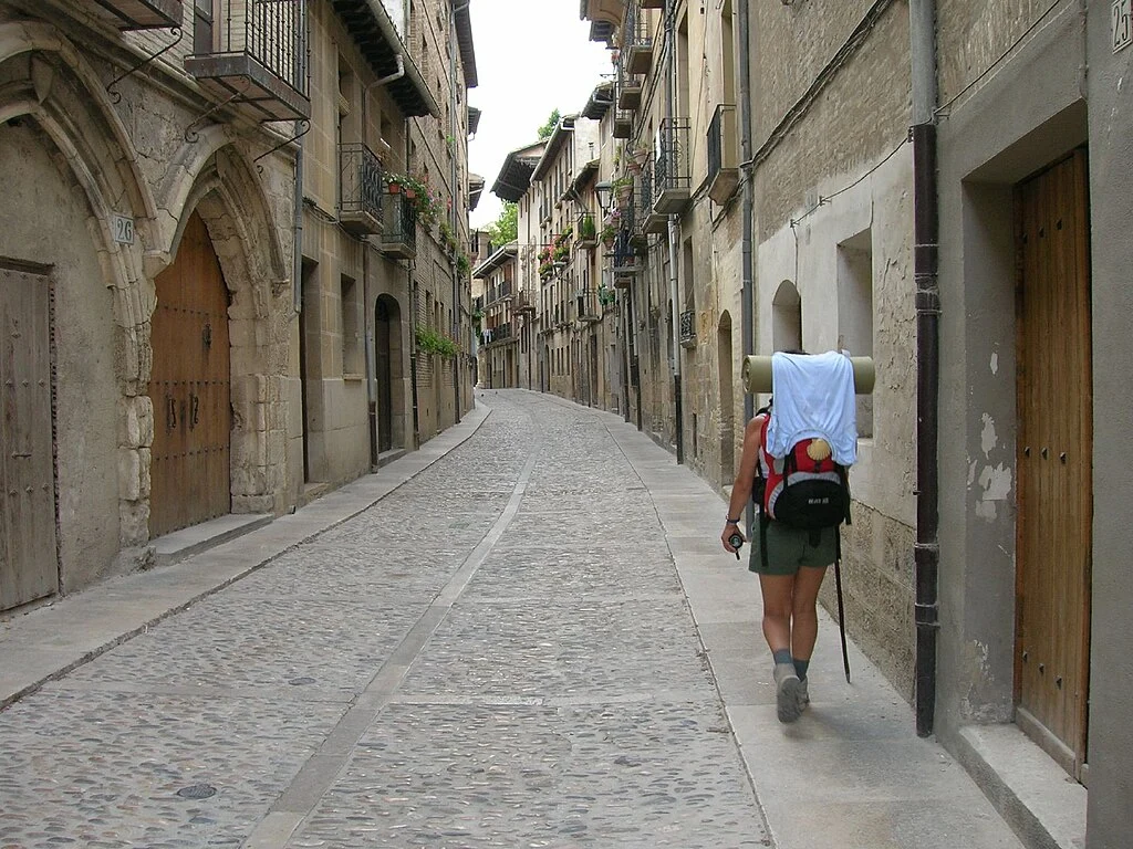 Peregrino caminhando por rua histórica do Caminho de Santiago de Compostela, na Espanha. O filme aborda o drama de um pai ao longo do Caminho, mostrando por que o filme O Caminho é uma jornada para muitas experiências nesta vida.