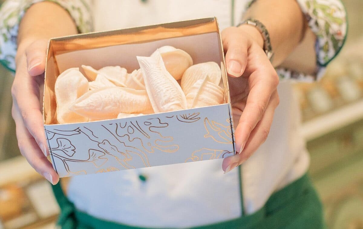 Ovos moles em recipiente branco, acompanhados de doces envolvidos em hóstia e embalagem da Confeitaria Peixinho, ilustrando artigo Doces de ovos em Portugal: como o açúcar ligou lugares?