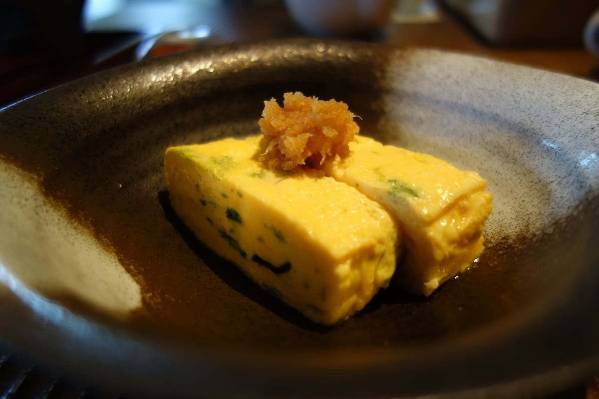 Tamagoyaki com espinafre, servido em fatias e acompanhado de daikon ralado. Ilustrando artigo Ovos: técnicas de preparo e tradições à mesa