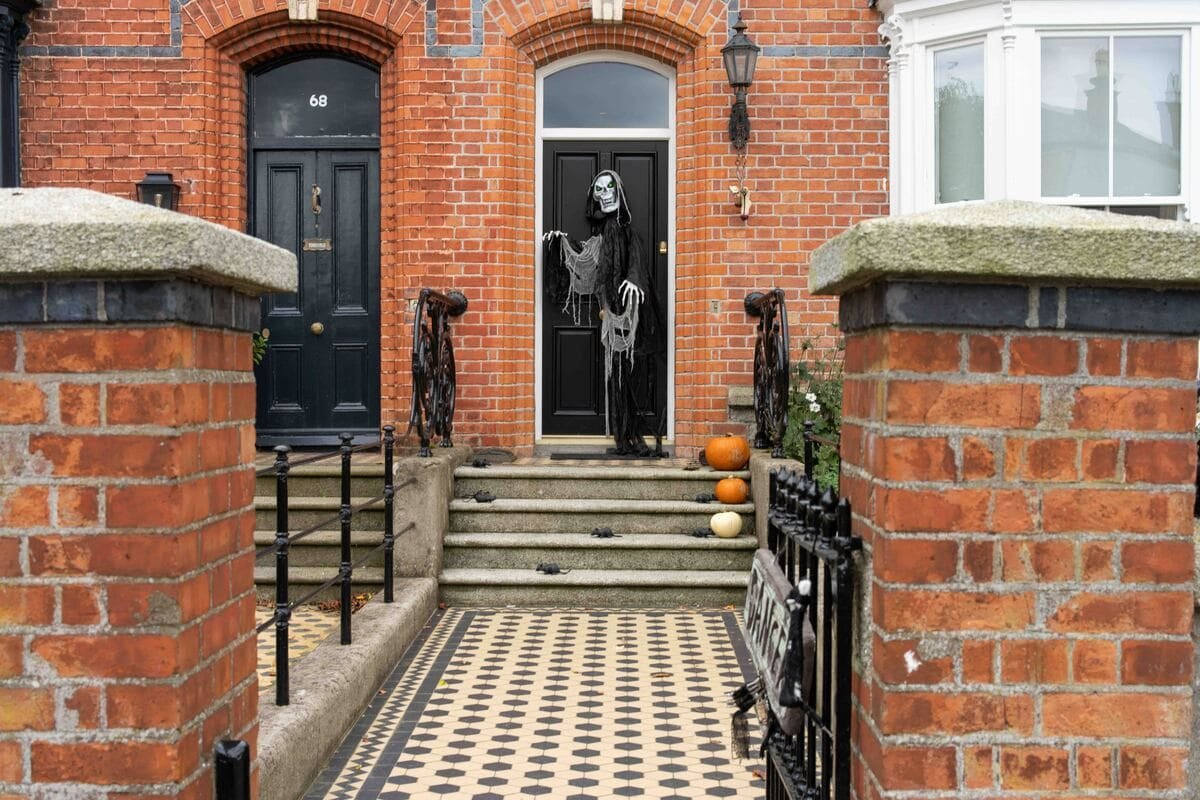 Casa em Dublin decorada para o Halloween, com abóboras nos degraus e uma figura assustadora junto à porta. Ilustrando artigo Halloween na Irlanda: o que liga a festa ao Samhain.